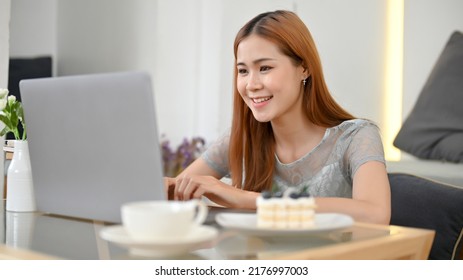 Attractive Millennial Asian Female Freelancer Or College Student Remote Woking At The Cafe, Using Laptop Computer.