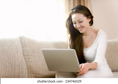 Attractive mixed female lifestyle using the laptop sitting on a couch