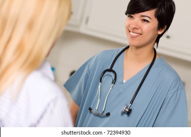 Attractive Mixed Race Young Female Doctor Talking With Patient In An Office Setting.