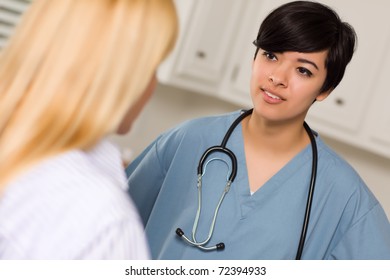 Attractive Mixed Race Young Female Doctor Talking With Patient In An Office Setting.