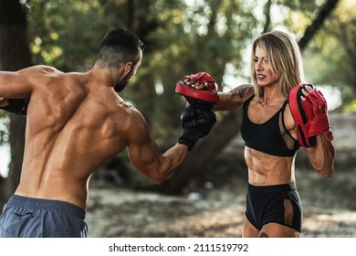 Attractive muscular mature woman sparring with a boxing partner at the nature. - Powered by Shutterstock
