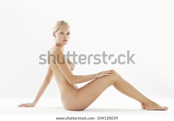 Attractive naked woman isolated on a white background, looking at camera while leaning back on her hand.