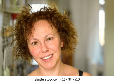 Attractive Natural Hispanic Woman With Curly Unruly Hair Giving The Camera A Quiet Smile On A Bad Hair Day Indoors At Home