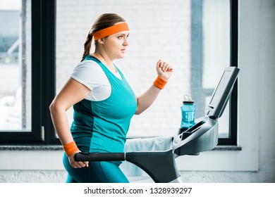attractive overweight girl workouting on treadmill in gym