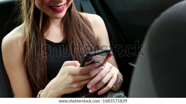 \
Attractive passenger young woman in\
backseat taxi car using cellphone and smiling to\
camera