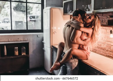 Attractive passionate couple is having sex on kitchen.