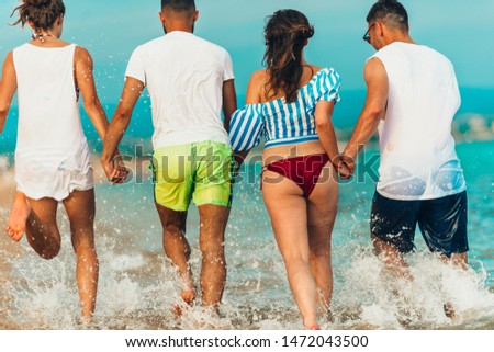 Attractive people on summer vacation jogging through sand beach in the dusk