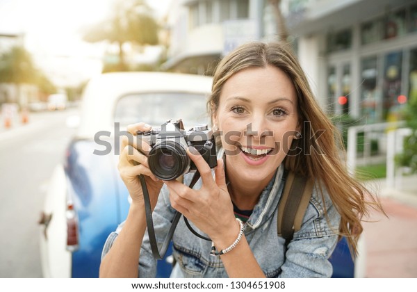 Attractive photographer taking photos with vintage\
camera in city