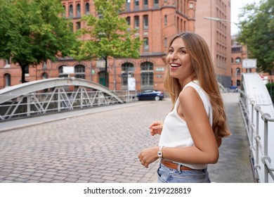 Attractive Positive Woman Turns Around And Looking To The Side In A Northern European City Street