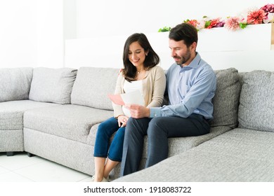 Attractive Pregnant Couple Expecting A Baby Sitting In The Doctor's Waiting Room While Reading The Medical Brochure 