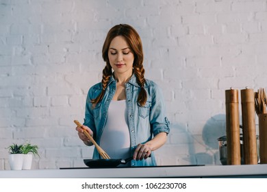 Attractive Pregnant Woman Cooking At Electric Stove At Kitchen