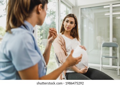 Attractive pregnant woman talking to nurse while waits for gynecologist check up. - Powered by Shutterstock