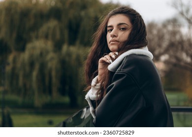 Attractive pretty woman standing outdoor on glass balcony, portrait of young lady dressed leather wool fur jacket, confident, serious, cold weather windy autumn spring
 - Powered by Shutterstock