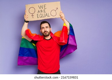 Attractive Queer Man With A Rainbow Flag Supporting Gay Rights And Gender Equality At A LGBT March 