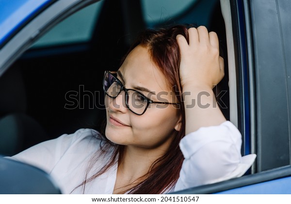 Attractive red hair woman stuck\
in a traffic jam. Running late. Angry woman driver stuck in\
traffic.