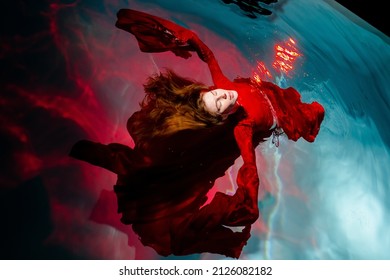 Attractive red-haired young woman swims beautifully underwater in a red dress. - Powered by Shutterstock