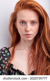 Attractive Redhead Young Female In Black Dress Looking At Camera Confidently, Isolated On White Studio Background. Serious Female With Natural Long Red Hair Having No Make-up. Copy Space. People
