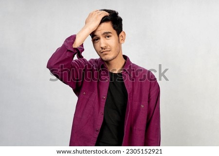 an attractive sad Asian man looking at camera while he is disorderly  fraught , messy , muddy and  turbulent  as if something wrong happened , not knowing what to do , bad feeling  negative emotion