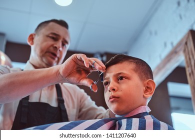 Attractive School Boy Is Getting Trendy Haircut From Mature Hairdresser At Fashionable Hairdressing Salon.