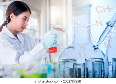 Attractive scientist woman looking chemical sample in flask at laboratory with lab glassware background. Science or chemistry research and development concept.