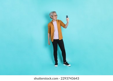 The attractive senior Asian man with yellow shirt standing on the green background. - Powered by Shutterstock