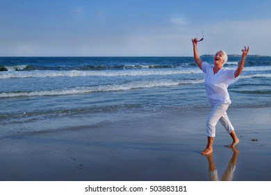 attractive senior grey haired woman dancing near sea shore. a woman dressed in a white blouse decorated with three rows of frills - Powered by Shutterstock