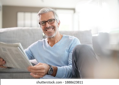 Attraktiver Senior Mann mit Brille entspannend zu Hause lesen Zeitung