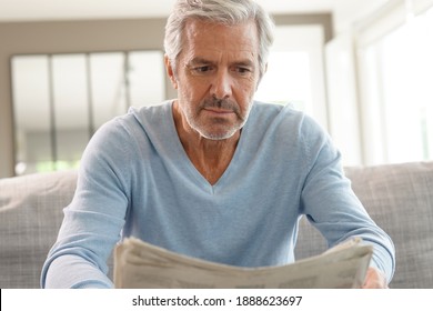 Attractive senior man relaxing at home reading newspaper