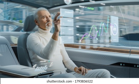Attractive Senior Man Using Futuristic Augmented Reality Interface for Reading News and Checking Social Activity while Sitting on a Backseat of Autonomous Car. Self-Driving Van Rides on Public Road.
