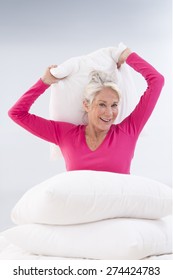 Attractive Senior Woman In Bed Having A Pillow Fight