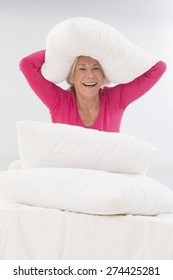 Attractive Senior Woman In Bed Having A Pillow Fight