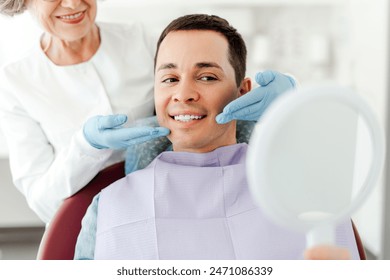 Attractive senior woman, dentist consulting male patient, sitting in dental chair. Professional doctor in modern clinic. Teeth treatment health care concept - Powered by Shutterstock