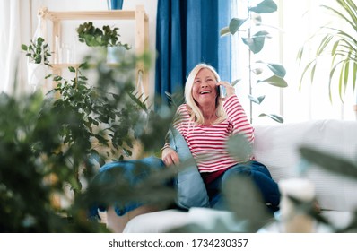 Attractive Senior Woman With Smartphone Sitting Indoors On Sofa, Making Phone Call.