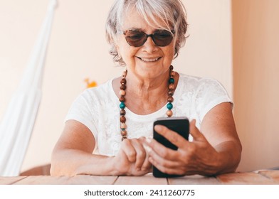 Attractive senior woman typing message on smartphone and smiling. Mature elderly woman enjoying tech and social - Powered by Shutterstock