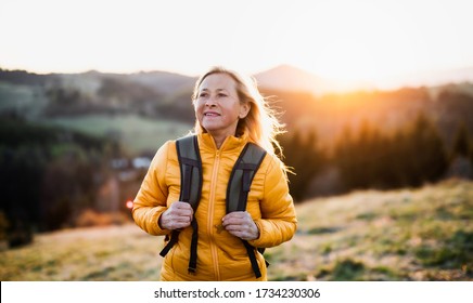 Attractive senior woman walking outdoors in nature at sunset, hiking. - Powered by Shutterstock