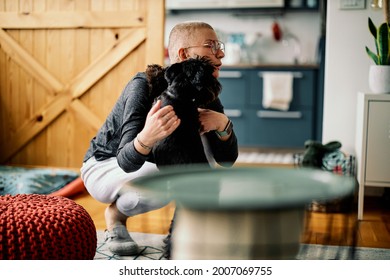 Attractive Senor Woman Kneeling And Playing With Her Dog At Home.