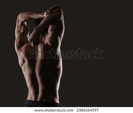 Attractive sensual man posing and showing off his muscular back, fitness and workout concept, copy space