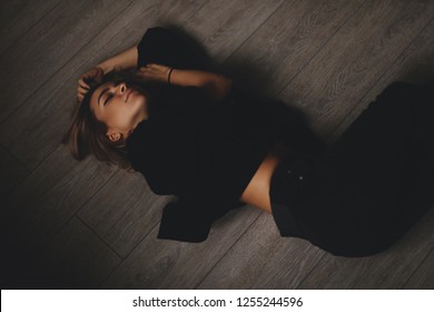 Attractive sexy woman lies on the floor. She looks sensuality. Hot girl wears total black look.