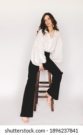 Attractive Sexy Woman Wear Business Look. Girl Look Sexy And Sensual. Elegant Look. Brunette Model Wear White Shirt, Gold Earrings And Black Pants. Winter, Fall Autumn Or Spring Minimal Outfit.