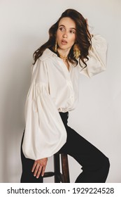 Attractive Sexy Woman Wear Business Look. Girl Look Surprised And Look At Back. Brunette Model Wear White Shirt, Gold Earrings And Black Pants. Winter, Fall Autumn Or Spring Minimal Outfit.