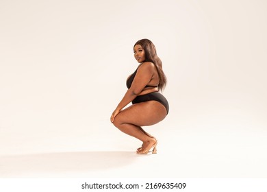 Attractive Sexywoman In Black Fashionable One Piece Swimsuit, Looking At The Camera. Full Photo Of Superb Plus Size Girl Posing In Studio On The Gray Background. Copy Space. Concept Of Body Acceptance