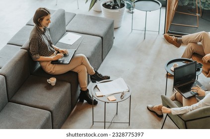 An attractive short haired business girl having a conversation with her colleagues and smiling while working on the lap top - Powered by Shutterstock