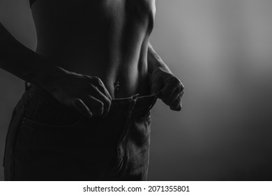 attractive, slender young woman in her thirties, dressed in wide jeans and a white shirt, demonstrates successful weight loss. concept of diet and weight loss.. Liposuction. bw. High quality photo