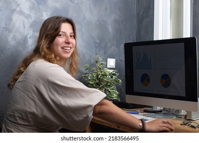 Attractive Smiling 25 Year Old Woman Working At Home On A Computer
