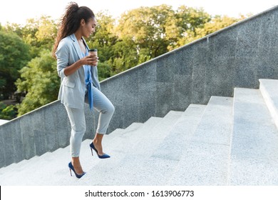 Attractive Smiling African Business Woman Walking Up The Stairs Outdoors At The City