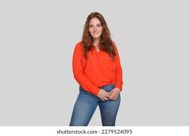 Attractive smiling curvy woman in red silk blouse posing on white background