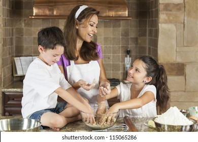 An Attractive Smiling Family Of Mother, And Two Children, Boy, Girl, Son, Daughter Baking And Eating Fresh Chocolate Chip Cookies In A Kitchen At Home