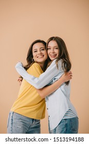 Attractive And Smiling Friends Hugging And Looking At Camera Isolated On Beige