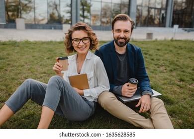 attractive smiling man and woman talking sitting on grass in urban park in smart casual business style working together on laptop, freelance people using technology, making notes - Shutterstock ID 1635628585