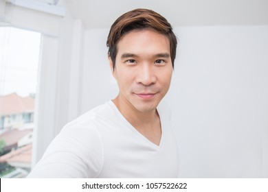 Attractive Smiling Positive Asian  Man Selfie With His Smartphone. Closeup Portrait Of Asian Handsome Guy With Isolated On White Background.